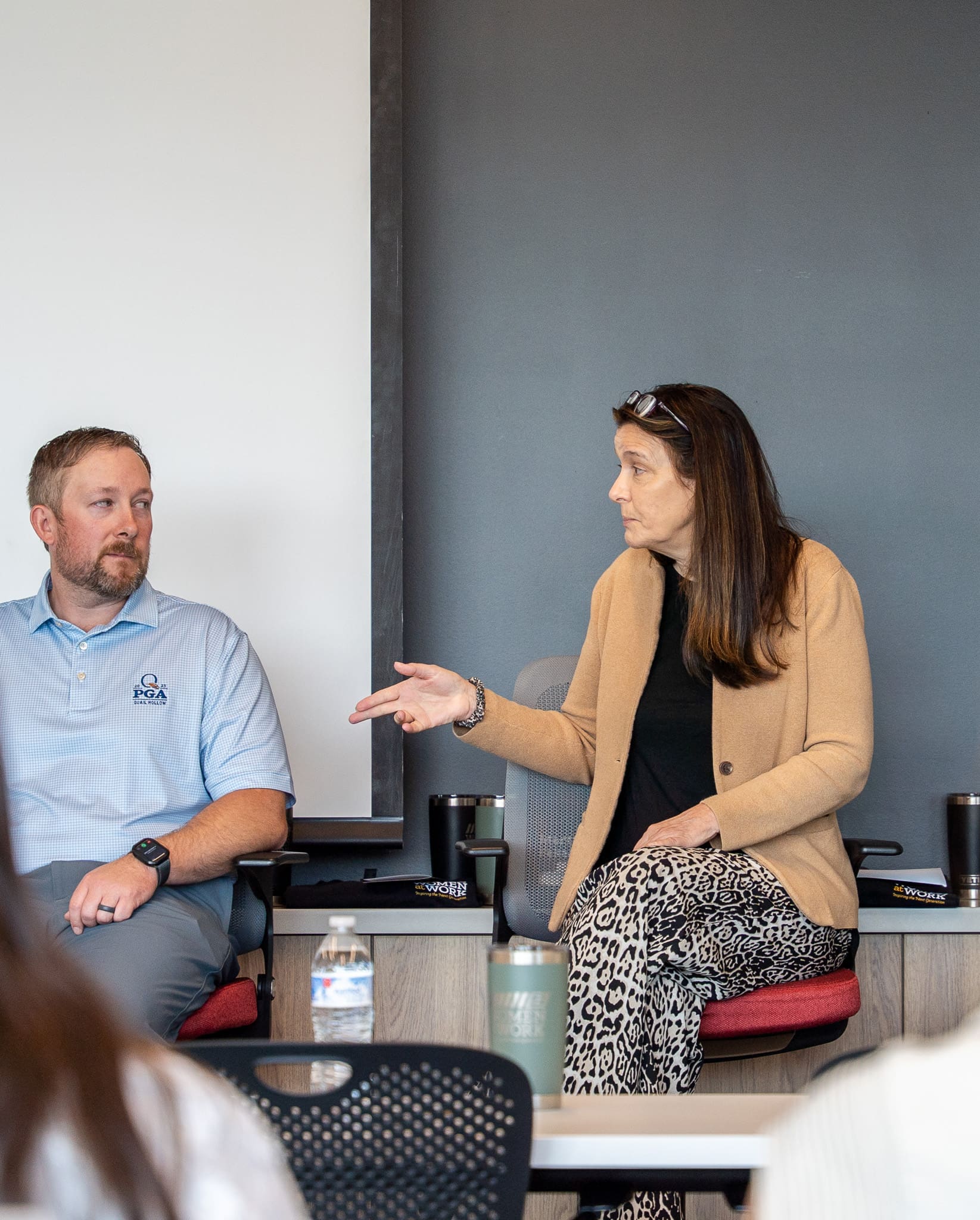 A wide view of the 2025 Women at Work panel hosted by Samet Corporation shows multiple women seated on stage, engaging in conversation with a full audience watching.