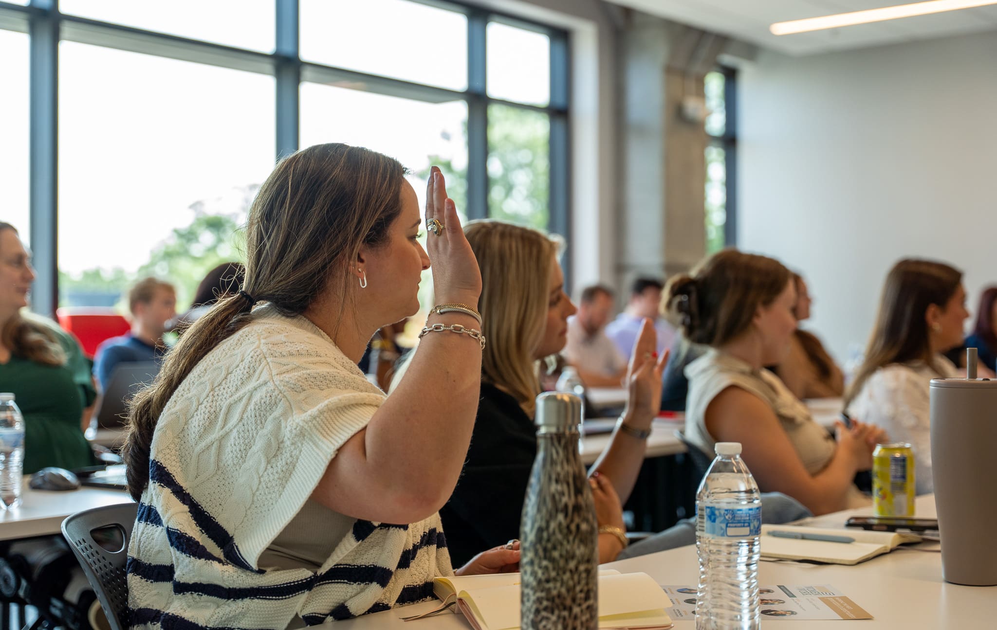 A woman gestures while speaking on a panel at Samet Corporation’s 2025 Women at Work event, with co-panelists seated beside her and audience members visible in the background.