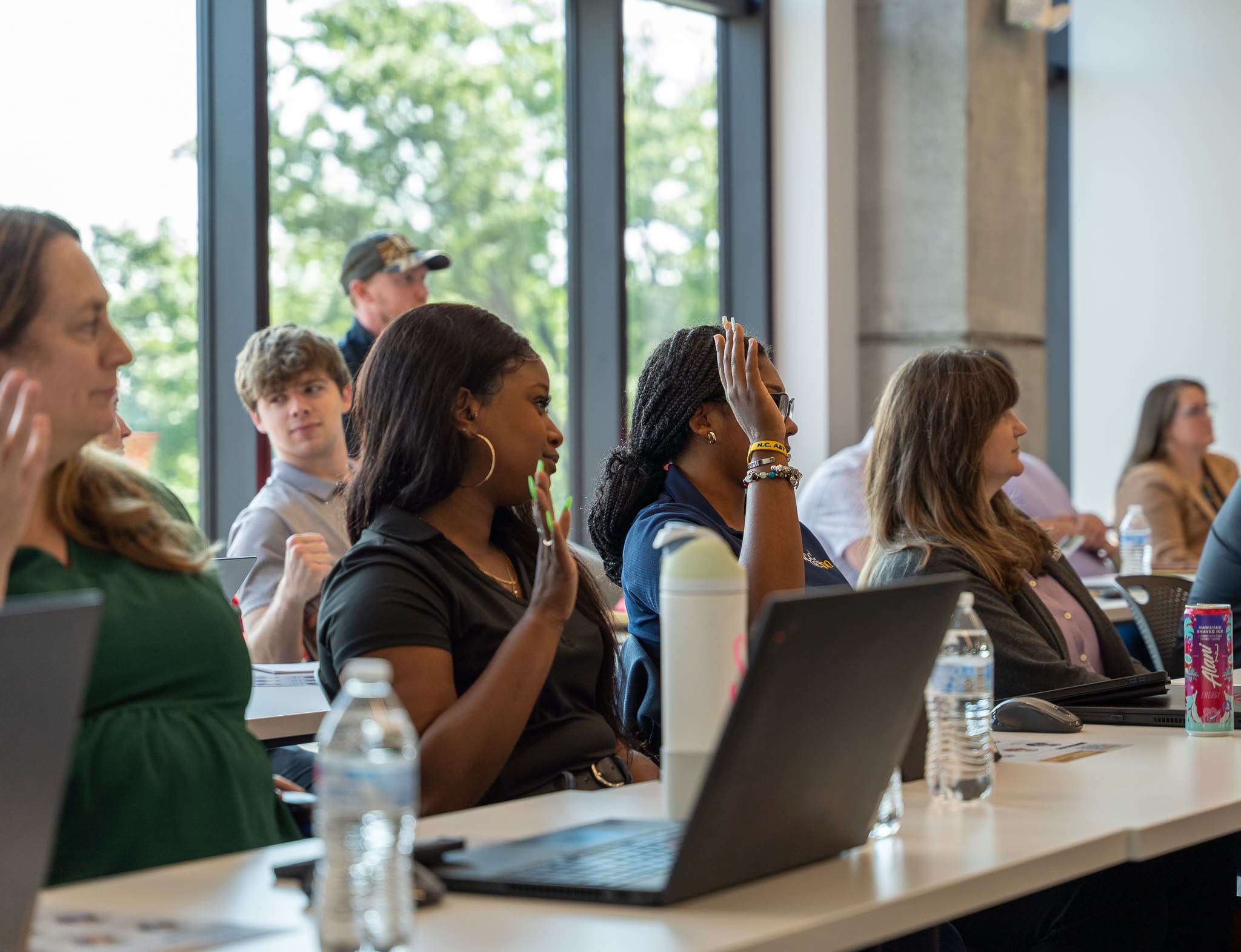 A panelist smiles while speaking into a microphone during the 2025 Women at Work event hosted by Samet Corporation, as others on stage listen and engage.