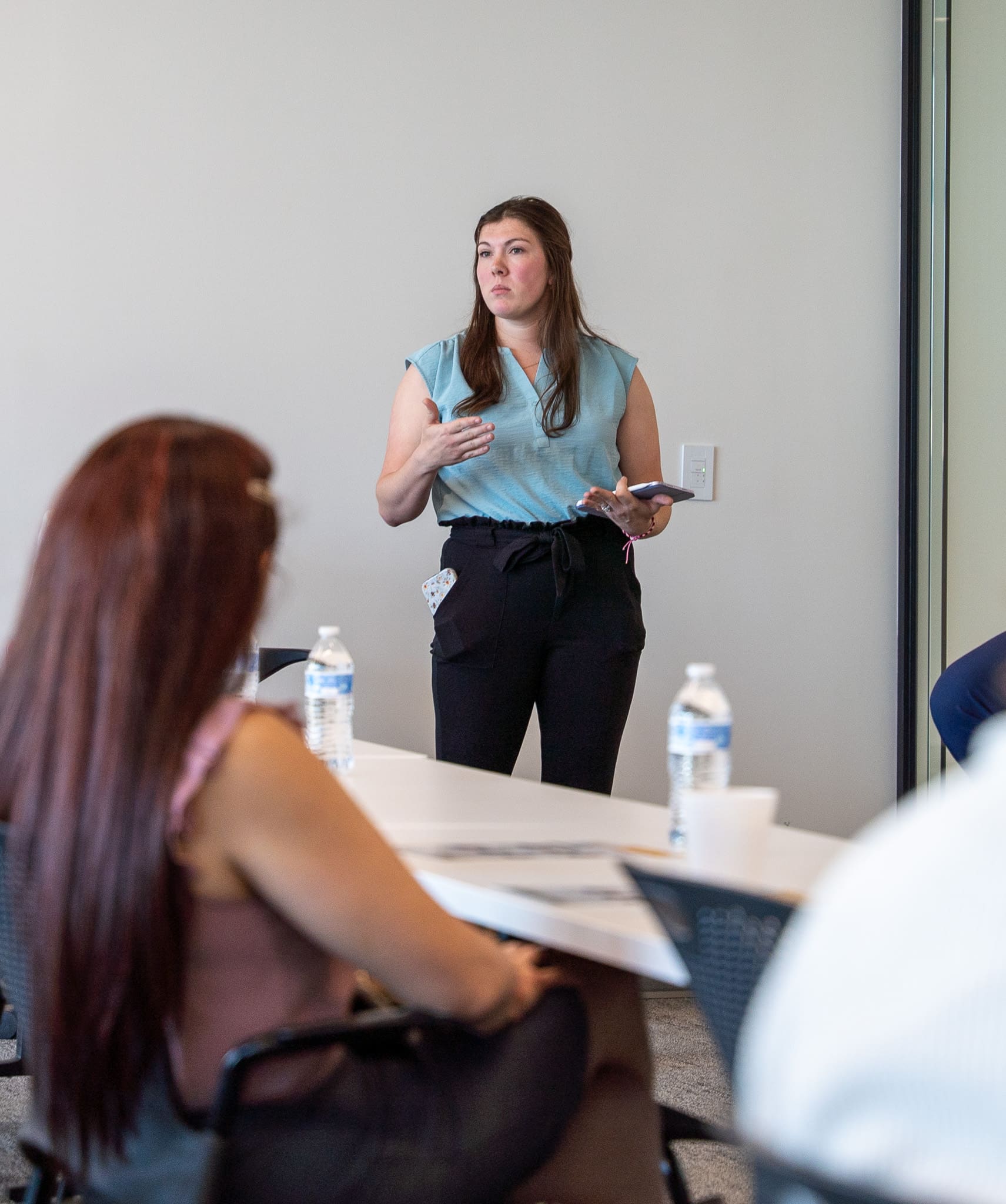 A woman speaks into a microphone while seated on a panel at Samet Corporation’s 2025 Women at Work event, with fellow panelists listening attentively.