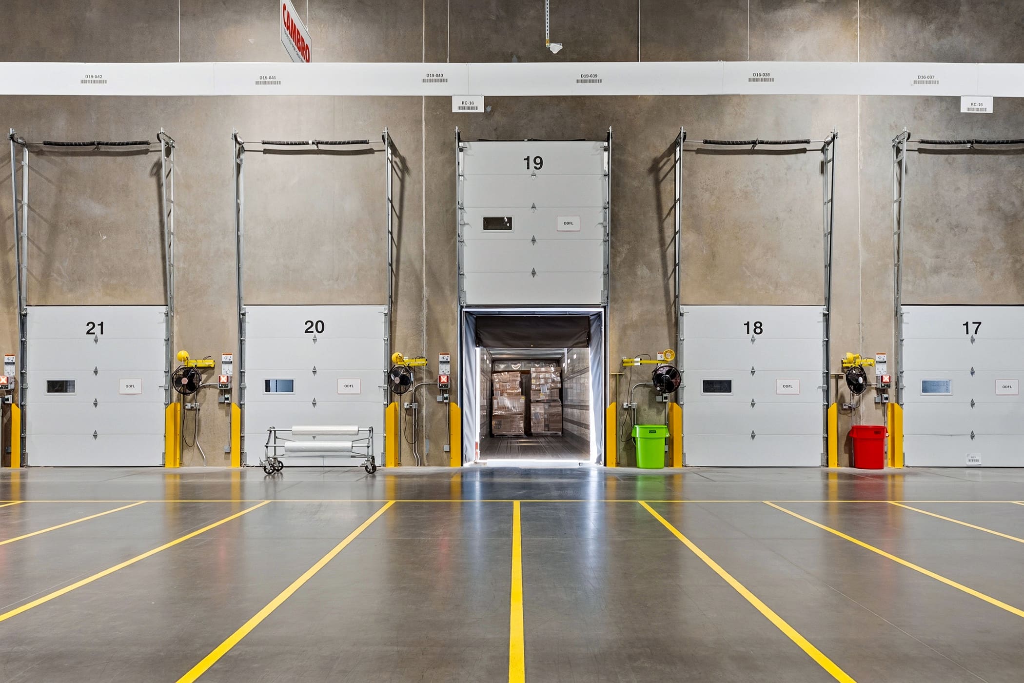 Warehouse loading dock doors with safety striping and dock levelers